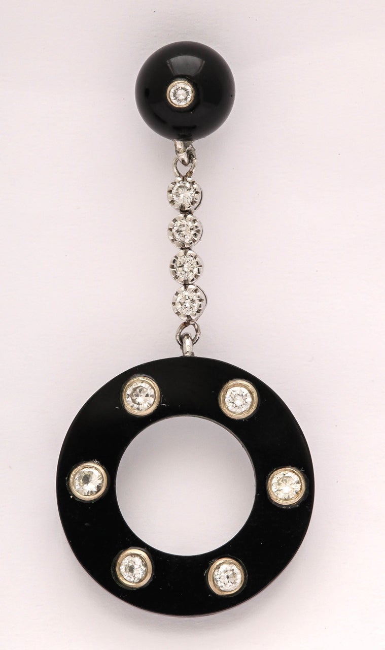 Super look.  Black Onyx Bezel set in 18kt White Gold with full cut lear white Diamonds.  Suspended from a round Black Onyx Bead  with a Diamond & suspended from a chain of Bezel set Diamonds.  Pierced
